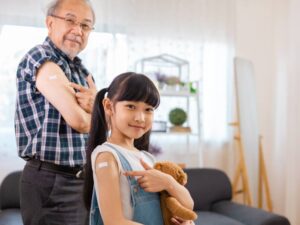 予防接種後に立つ老人男性と少女の画像
