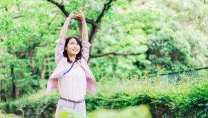 緑の中で伸びをする女性