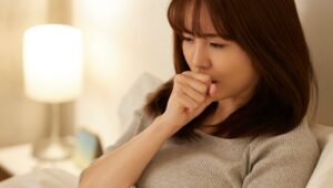 ベッドの上で咳き込む女性のイメージ