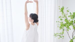 朝の光の中で両手を上げ、深呼吸をしている女性